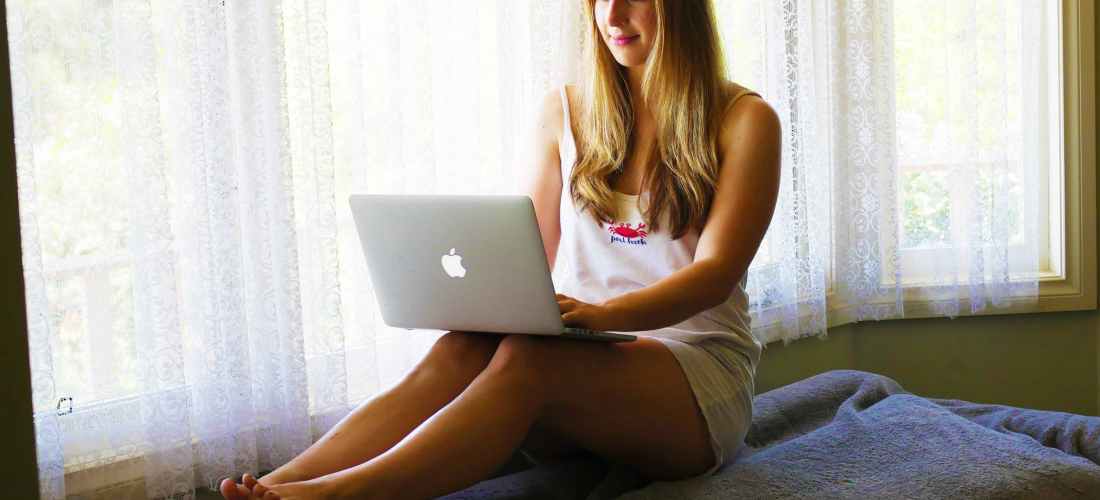 girl on laptop typing on keyboard by window